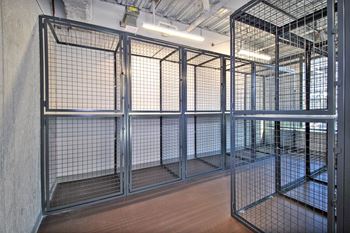 a group of cages in a room with wood floors and metal doors
