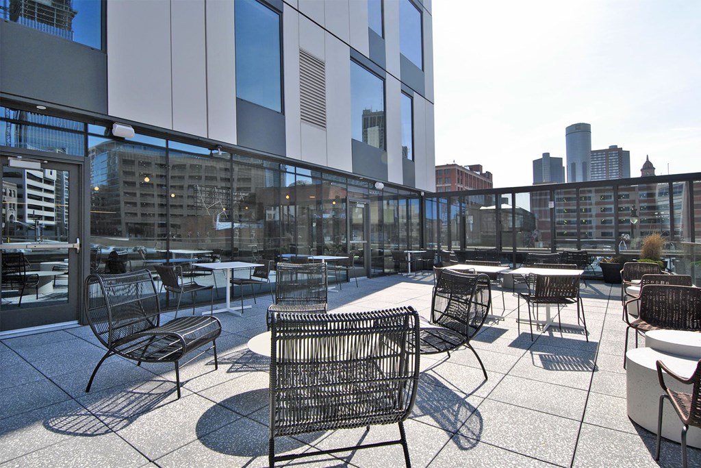 a rooftop patio with tables and chairs and a city in the background