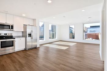 an empty living room with a kitchen and a large window