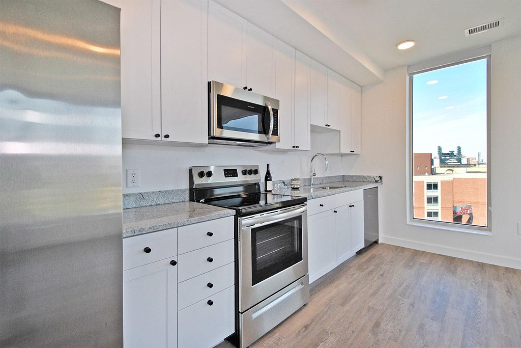 a kitchen with white cabinets and stainless steel appliances and a window