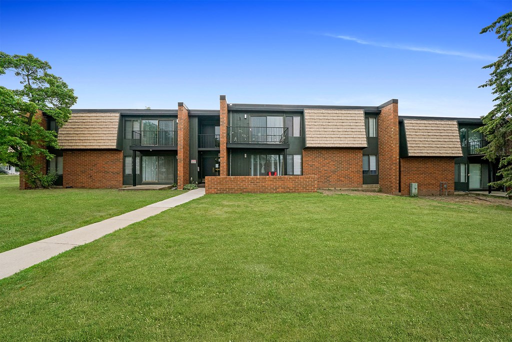 the front of a brick apartment building with a green lawn