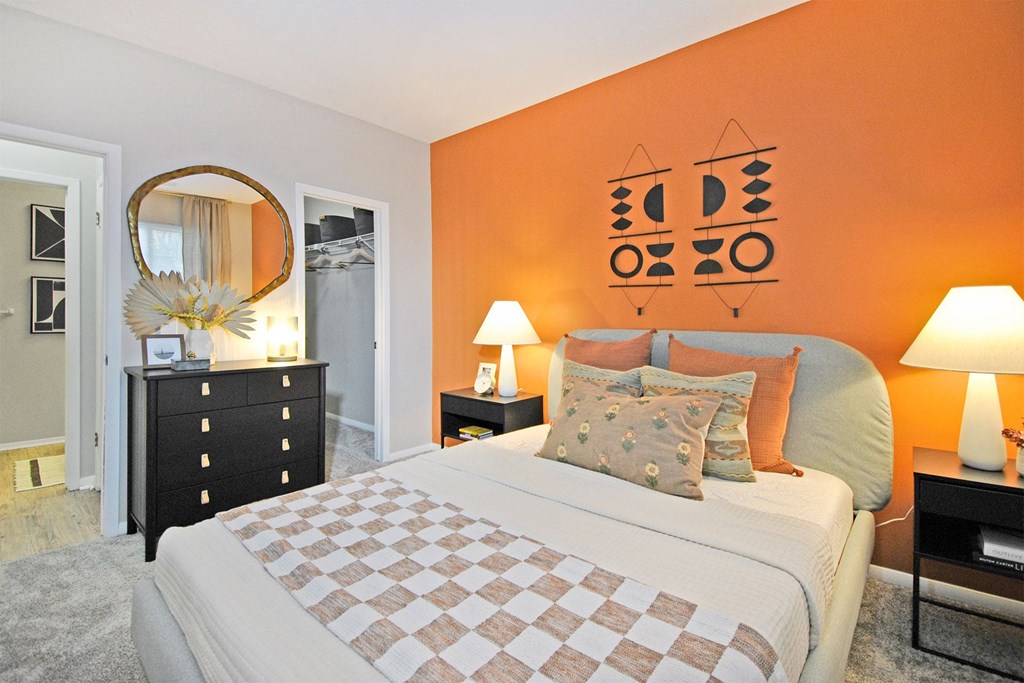 a bedroom with an orange accent wall and a large bed