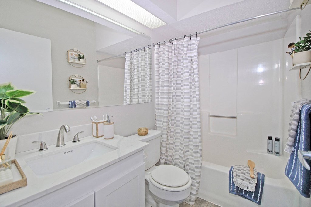 a white bathroom with a shower curtain and a toilet and sink