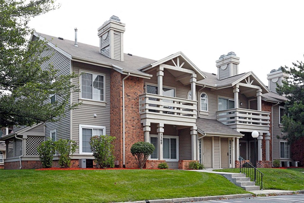 two story apartment building exterior with balconies and green grass