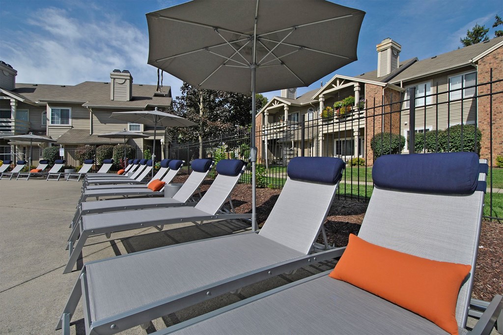 a row of lounge chairs and umbrellas in front of apartments