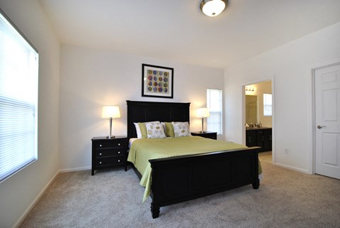 A bedroom with a bed, nightstands, and a mirror.