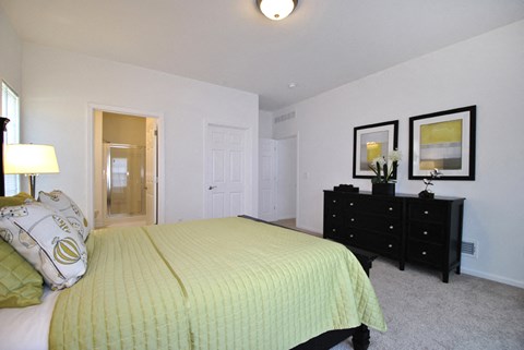 A bedroom with a bed, dresser, and two framed pictures on the wall.