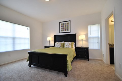 A bedroom with a bed, nightstands, and a window.