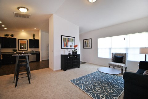 A living room with a black couch, a round table, and a rug with a geometric pattern.