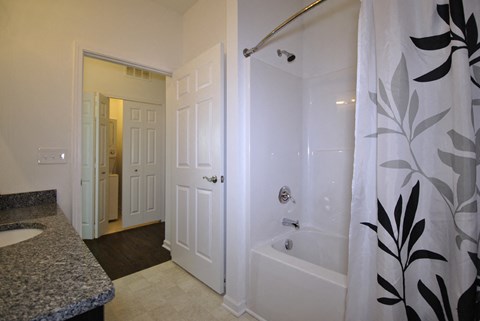 A white bathroom with a shower curtain and a sink.