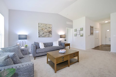 A living room with a grey couch and a wooden coffee table.