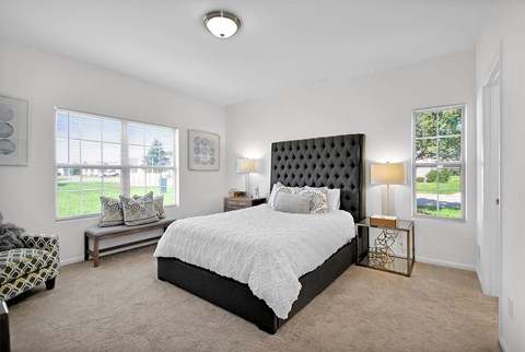 A bedroom with a large bed and a bench in front of a window.