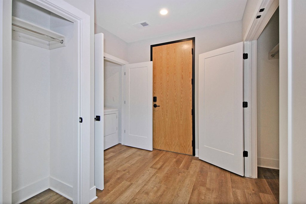 a hallway with white walls and wood floors and a wooden door