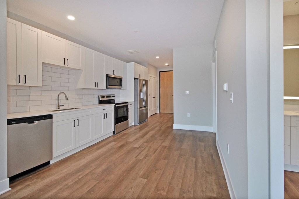 an empty kitchen with white cabinets and a wooden floor