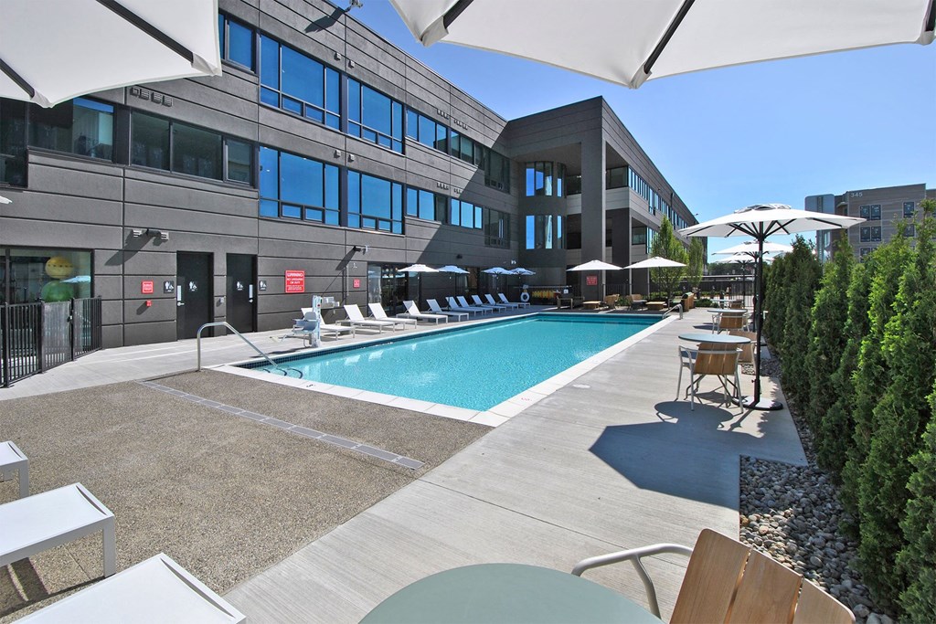 a swimming pool with lounge chairs and umbrellas in front of a building