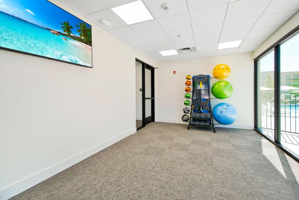 an empty room with a gym with weights and balls on the wall