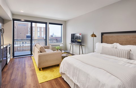 A bedroom with a large bed and a balcony overlooking the city.