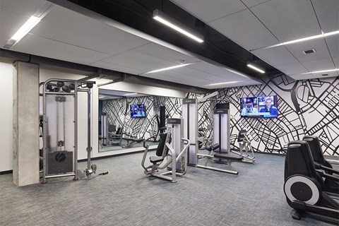 A gym with a variety of equipment including a treadmill, weights, and a television.
