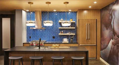 A kitchen with a bar area and a blue tile backsplash.