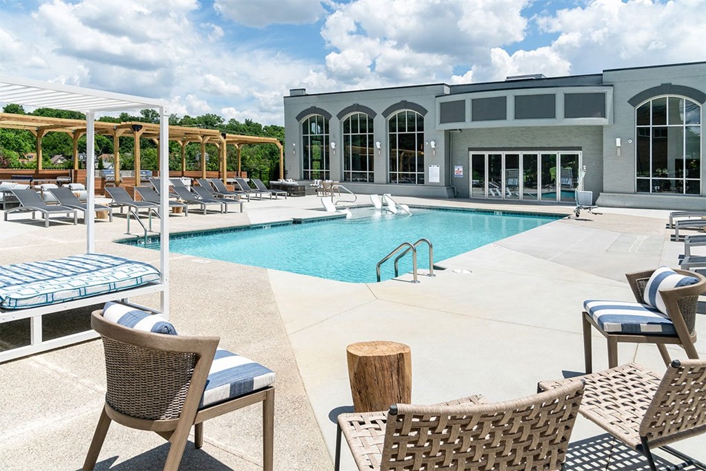 a swimming pool with chairs and a building in the background