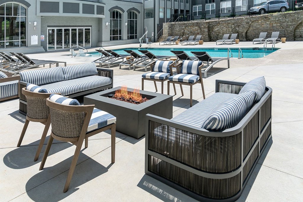 a pool with lounge chairs and a fire pit