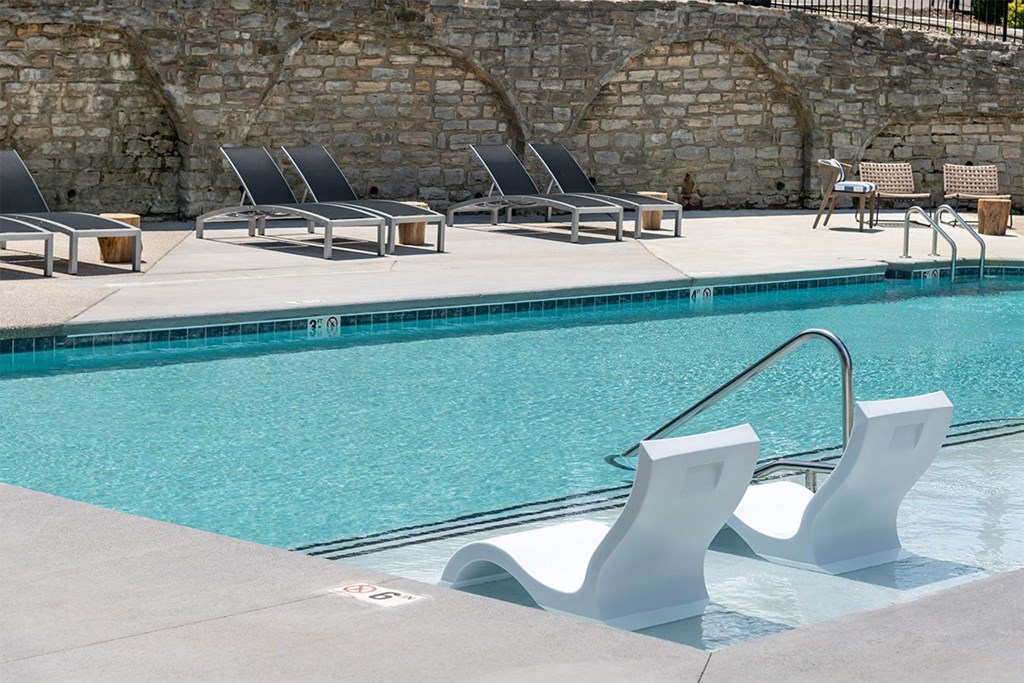 a swimming pool with white chairs and a blue water