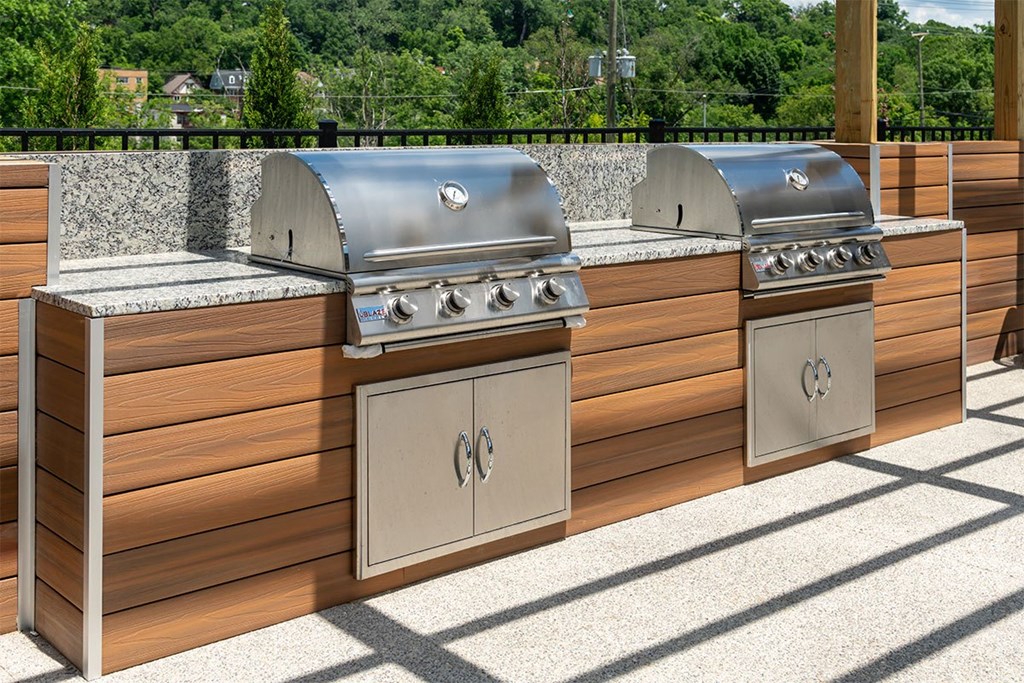 two stainless steel barbecue grills next to each other on a patio