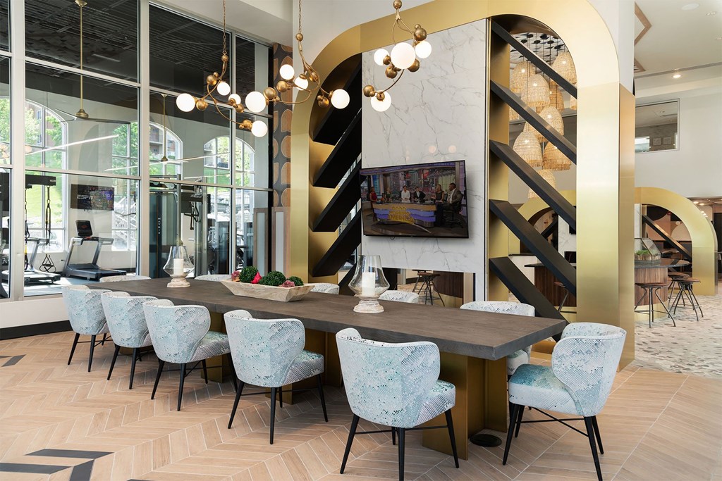 a dining room with a long table and chairs and a staircase
