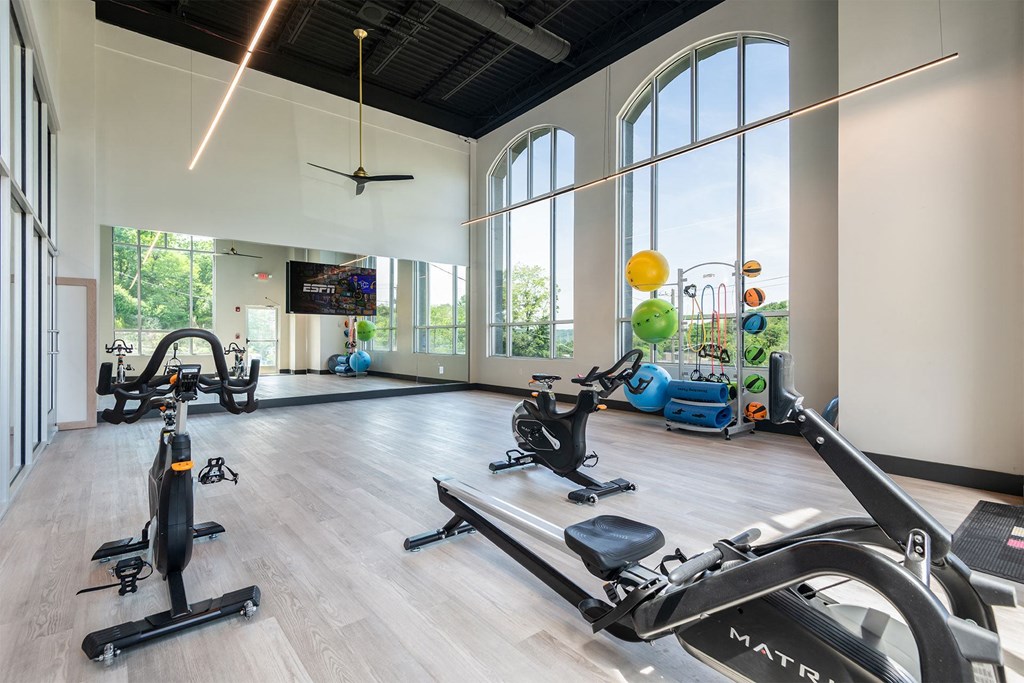 a gym with treadmills and other exercise equipment and large windows