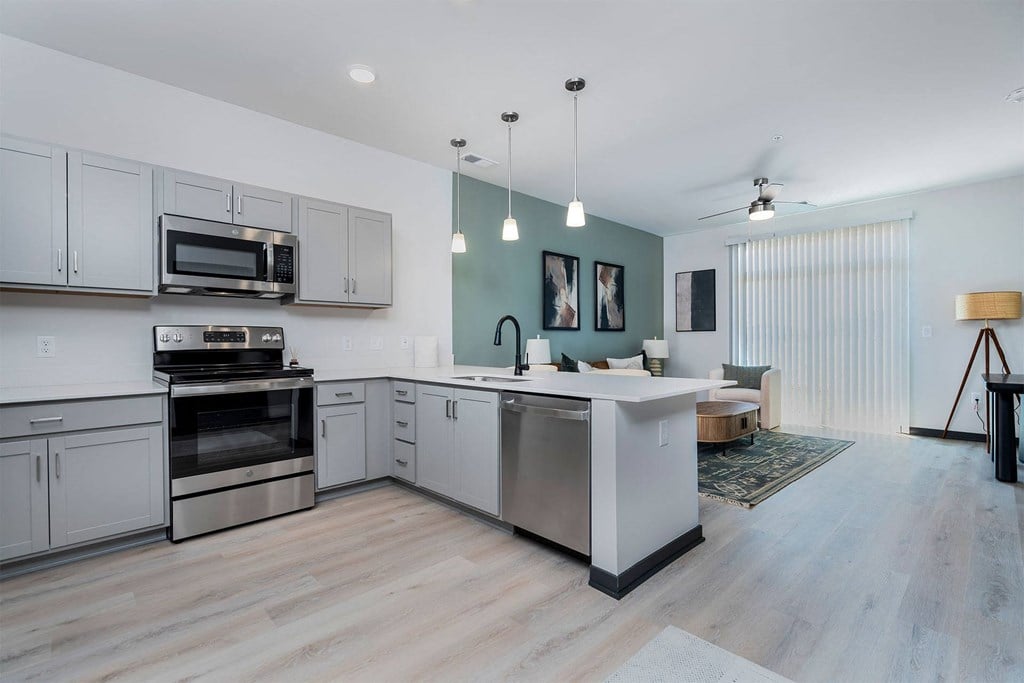 a kitchen and living room with white cabinets and stainless steel appliances
