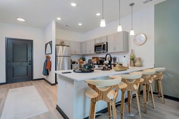 A kitchen with a white counter and bar stools.