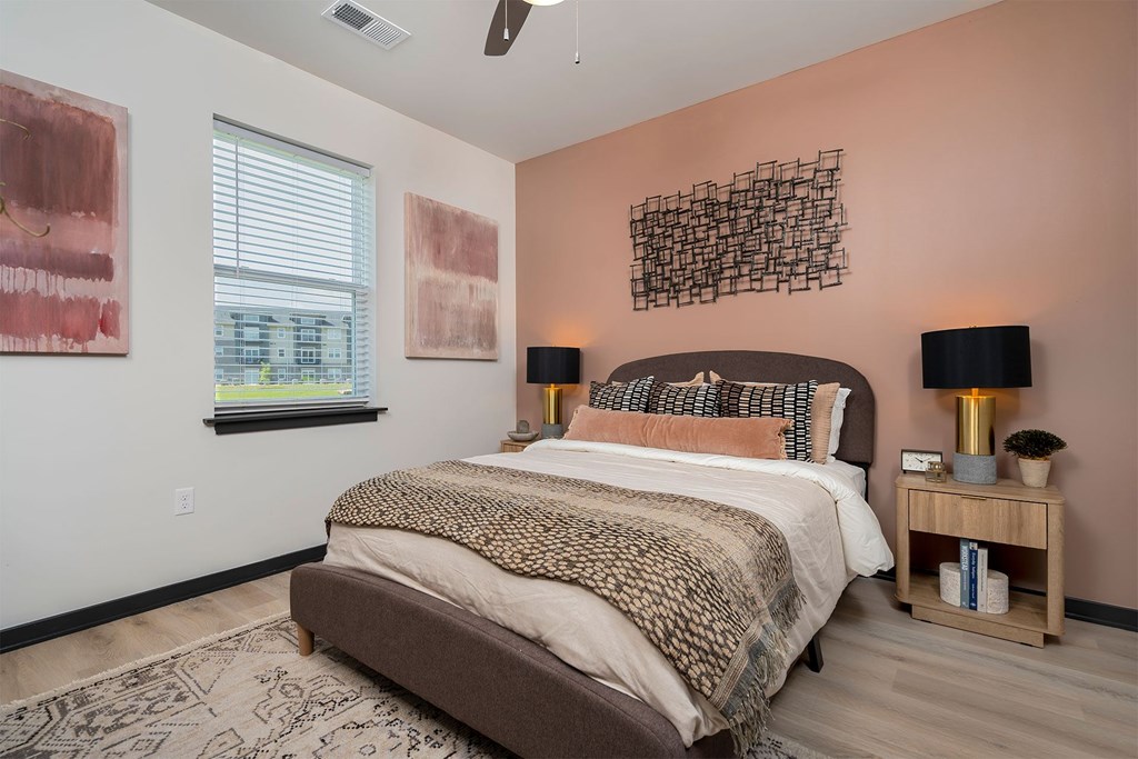 A bedroom with a large bed and two lamps.