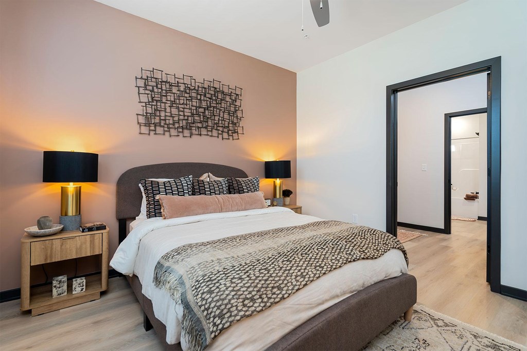 A bedroom with a large bed and a lamp on a side table.