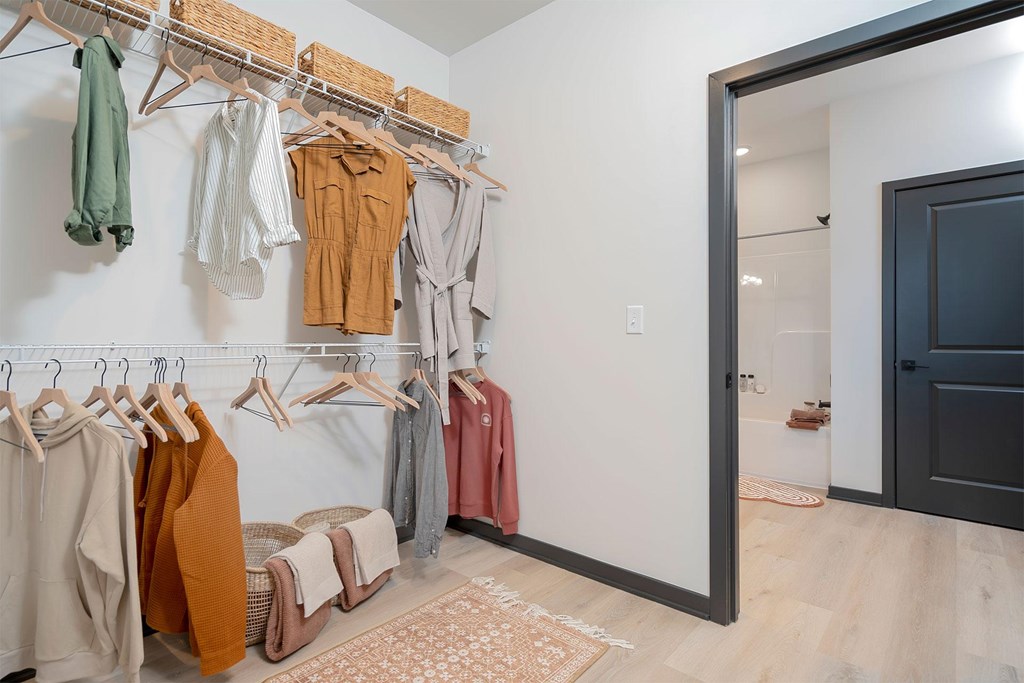 A row of clothes are hung on a rack in a room.