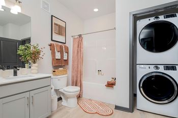 A modern bathroom with a washer and dryer built into the wall.