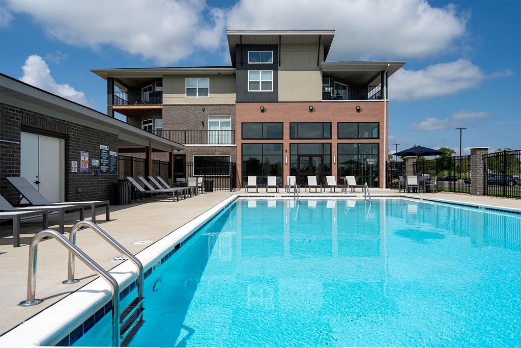 A large swimming pool in front of a multi-story residential building.