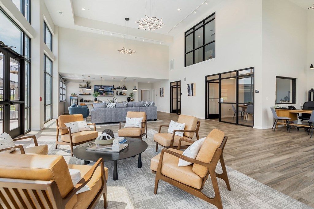A modern living room with a glass table surrounded by leather chairs.