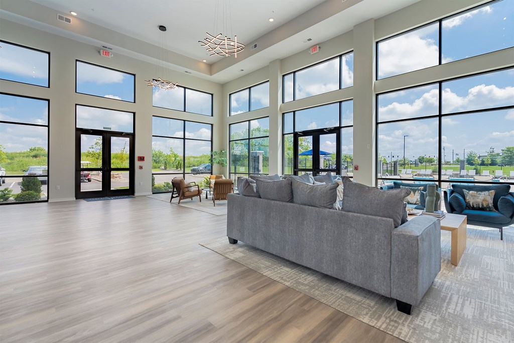A spacious living room with a grey sofa and wooden flooring.
