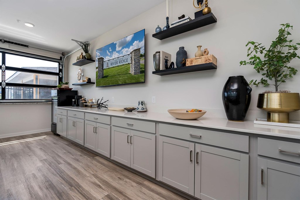 A kitchen with a large painting of a house on the wall.