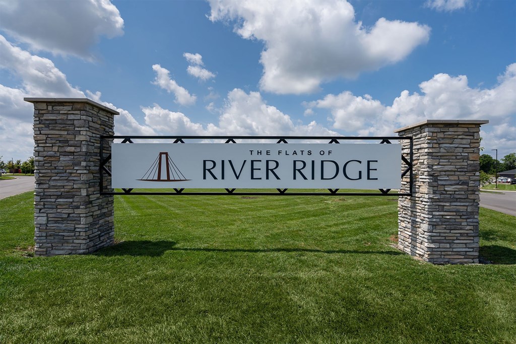 A sign that says River Ridge stands in a grassy field.