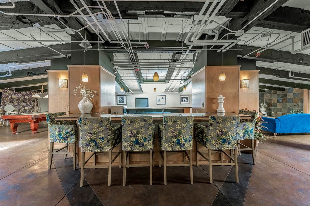 a long bar with chairs and a table in a lobby