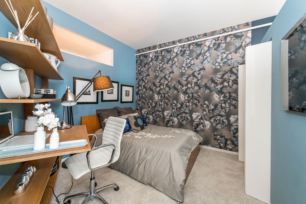 a bedroom with blue walls and a bed and a desk