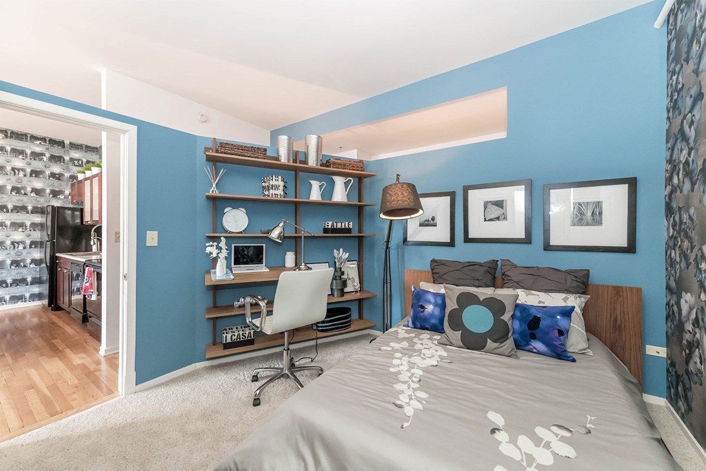 a bedroom with a bed and a blue wall and a desk