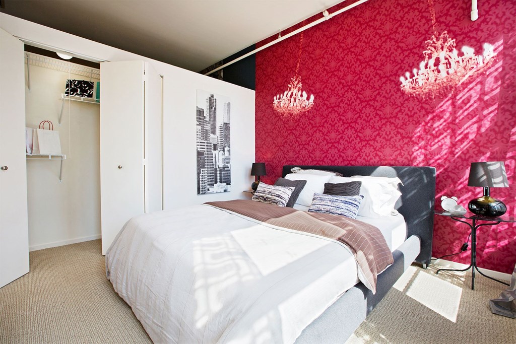 a bedroom with a red wall and a white bed