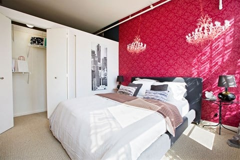 a bedroom with a red wall and a white bed