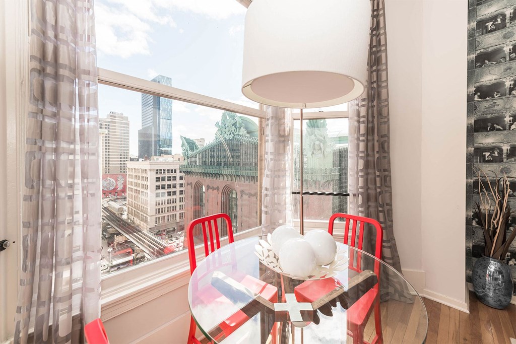 a dining room with a large window and a table with red chairs
