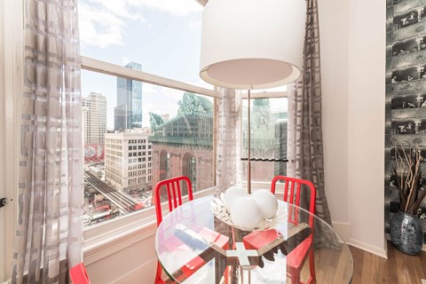 a dining room with a large window and a table with red chairs