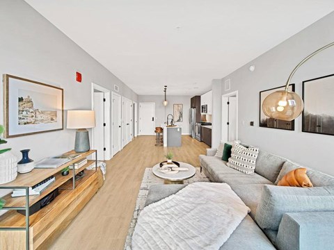 A well-lit, modern living room with a grey sofa and a wooden coffee table.