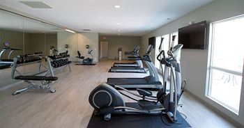 a gym with cardio equipment and a flat screen tv
