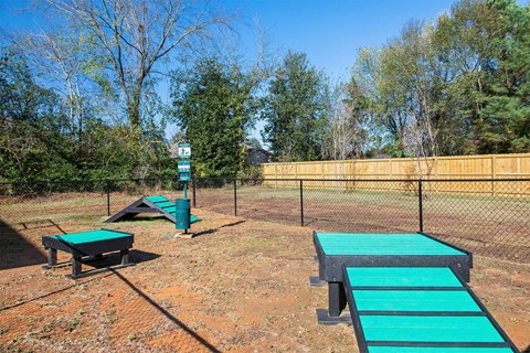 A playground with a green slide and a wooden fence.